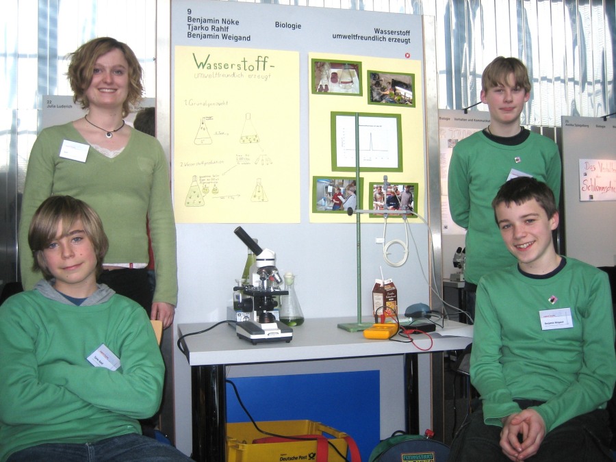 Tjarko, supervisor Vera Küppers, Benjamin W. and Benjamin N. in front of their exhibit about eco-friendly production of hydrogen