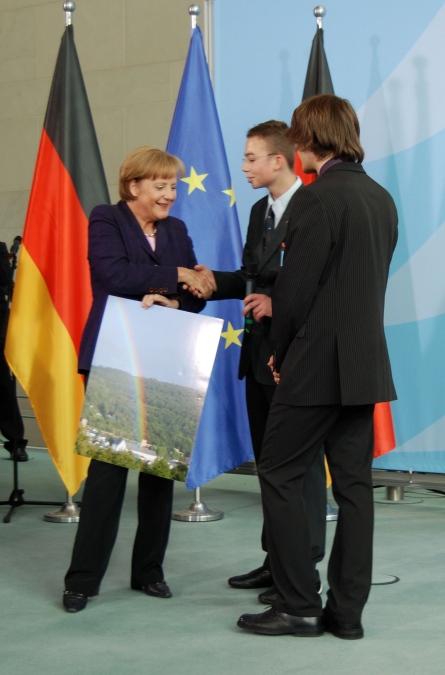 Tobias Kaufmann and Michael Schmitz give a picture of St. Michael-Gymnasium to German Chancellor Dr. Angela Merkel