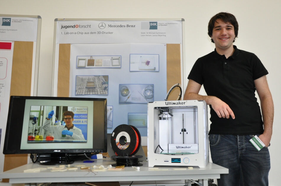Justus Beyerling auf dem Monitor und Leon Heinen an ihrem Stand mit dem 3D-Drucker